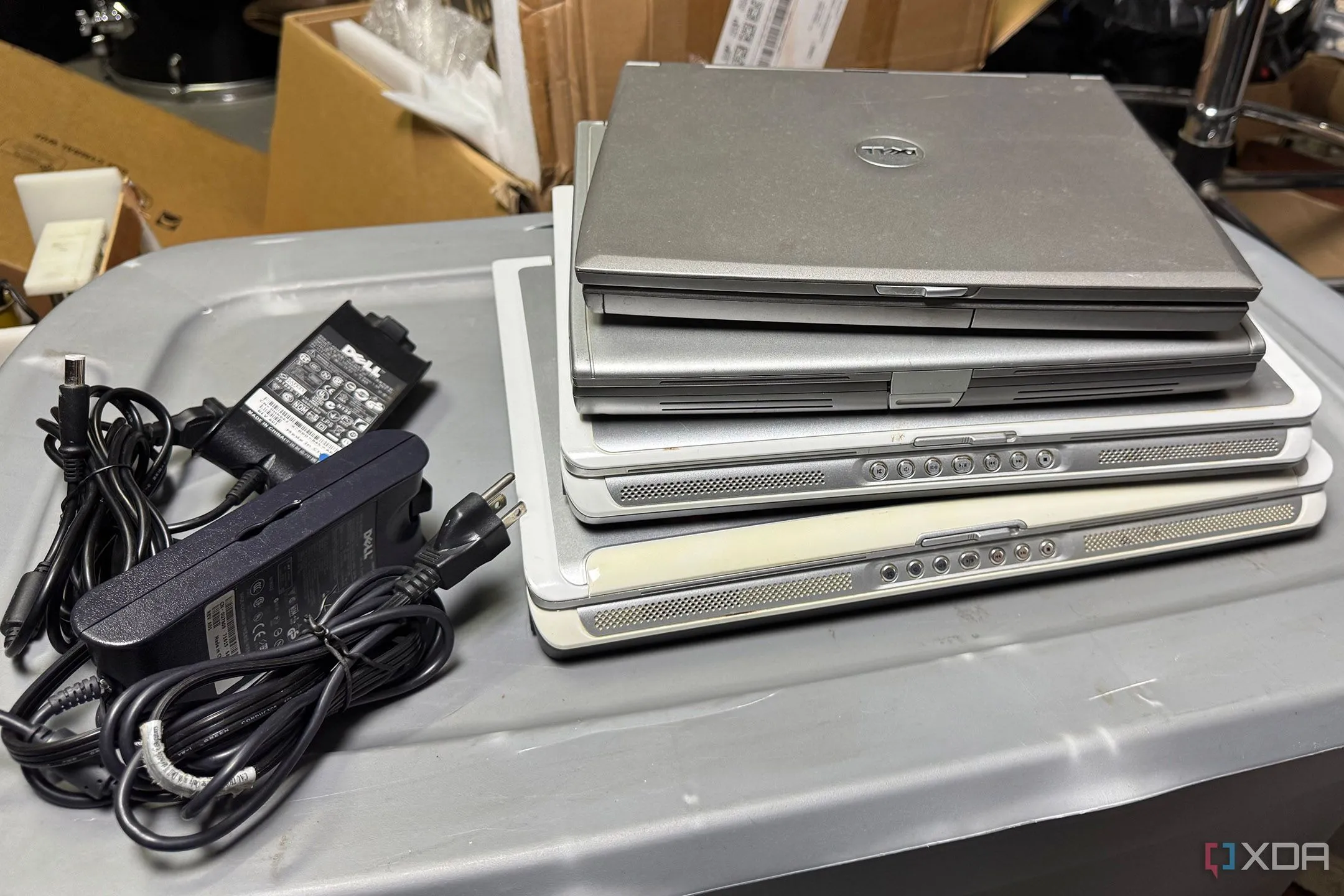 Chồng laptop cũ và bộ sạc thể hiện sự lãng phí tài nguyên công nghệ