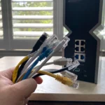 Hình ảnh bó cáp Ethernet nhiều màu sắc trước một bộ định tuyến