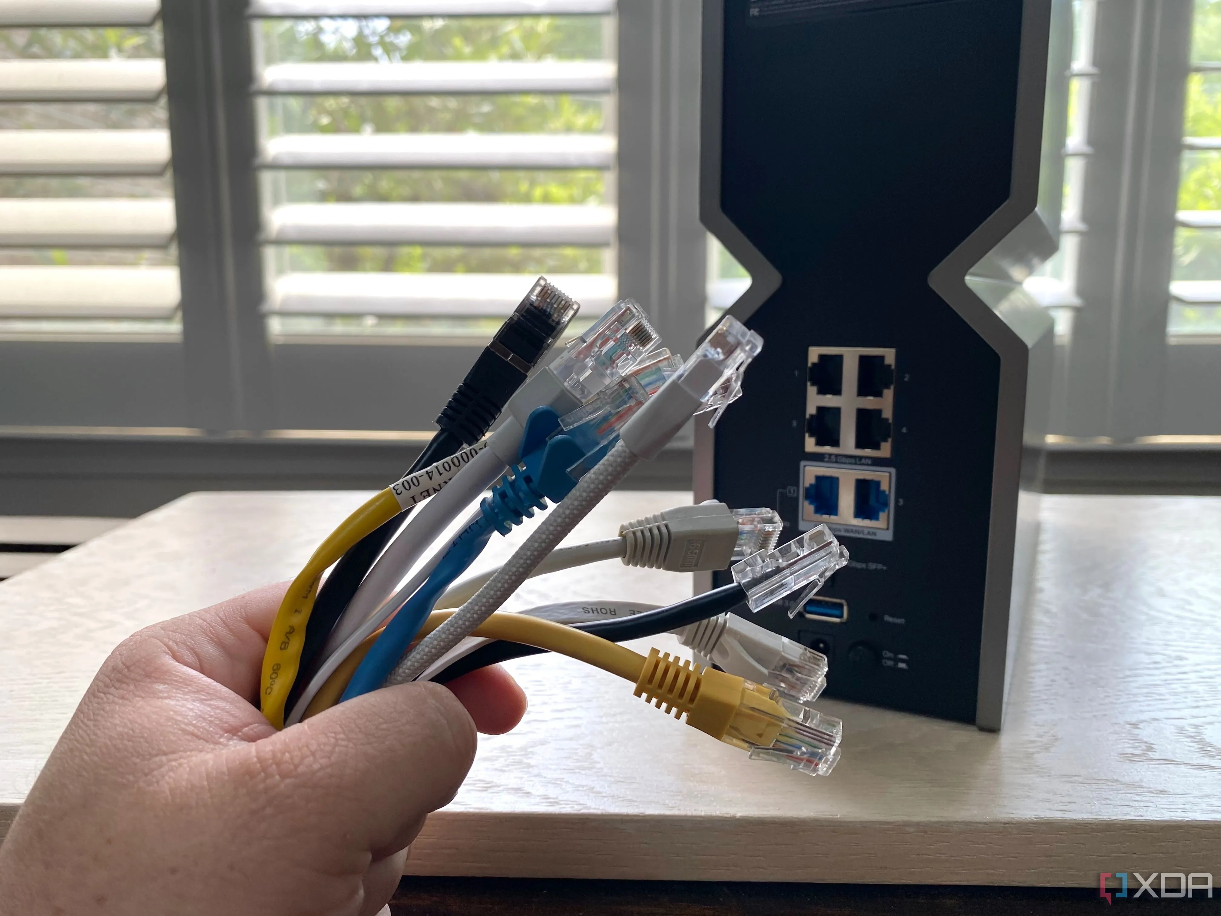 Hình ảnh bó cáp Ethernet nhiều màu sắc trước một bộ định tuyến