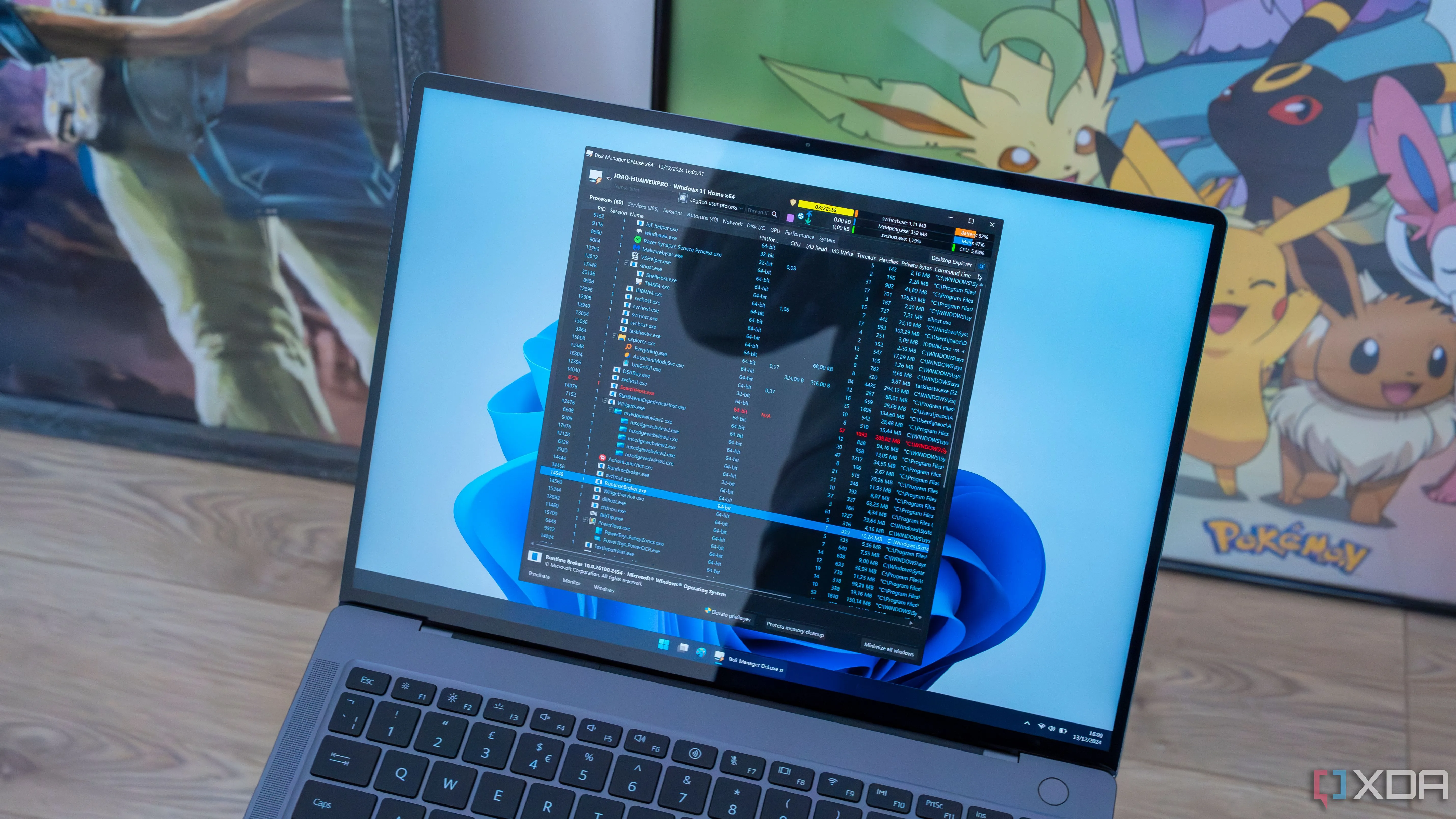 Laptop chạy Windows 11 hiển thị cửa sổ Task Manager DeLuxe với các tiến trình đang hoạt động