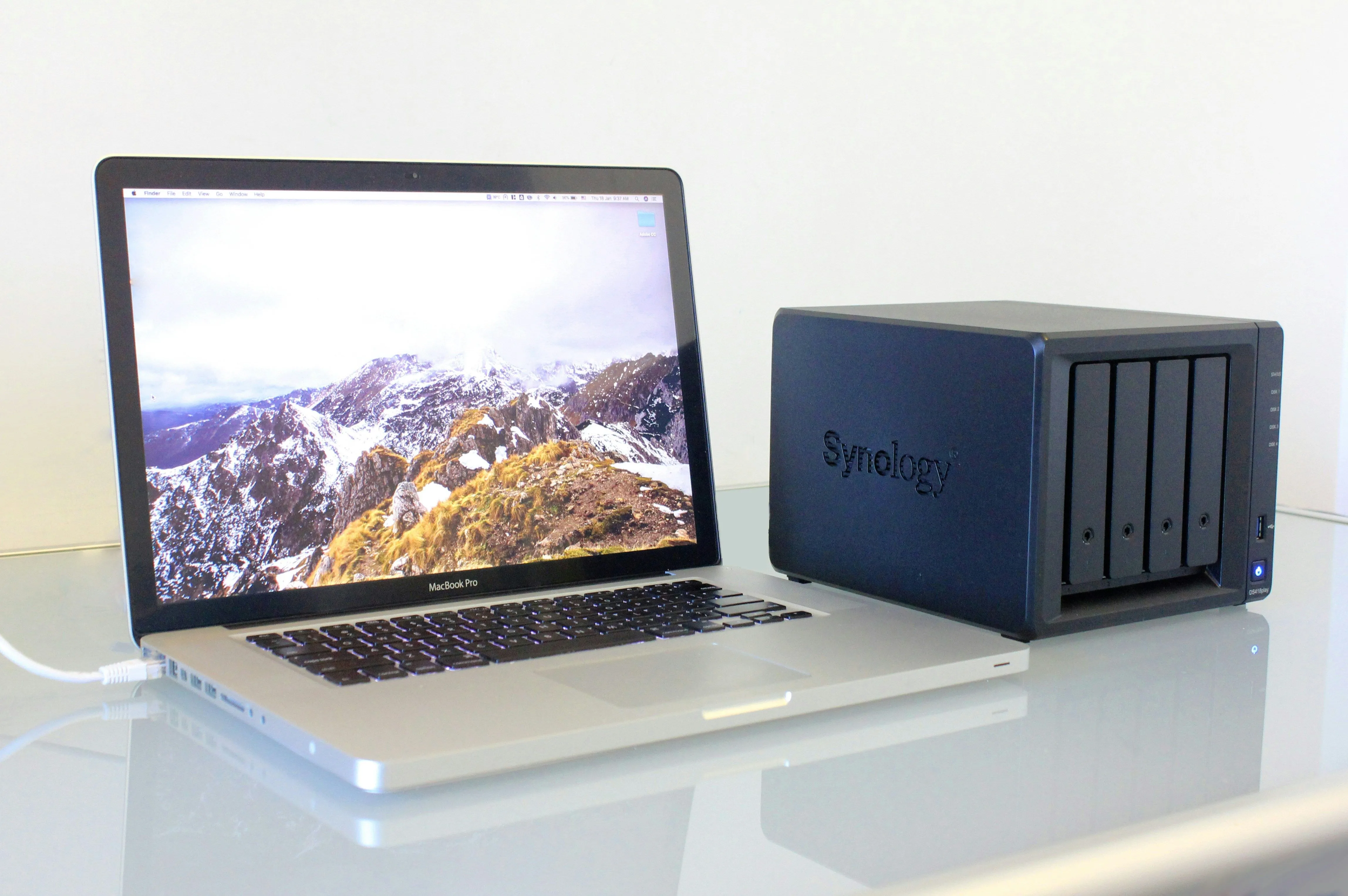 Máy tính MacBook Pro kết nối với thiết bị NAS Synology, tượng trưng cho việc sao lưu và đồng bộ dữ liệu