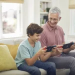 Một người đàn ông và một cậu bé đang vui vẻ chơi game trên Nintendo Switch, thể hiện tính thân thiện với gia đình của hệ máy này