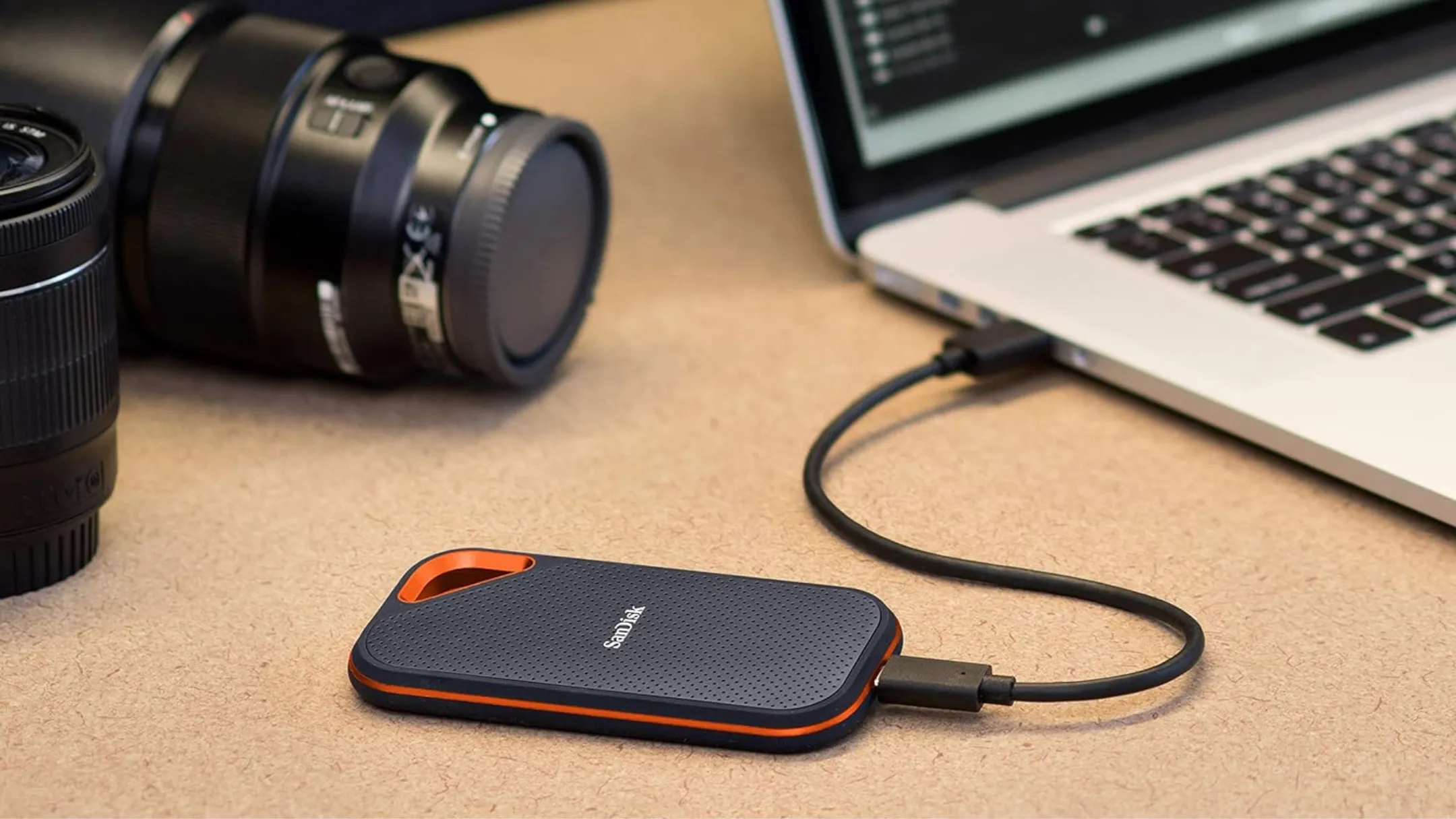 SanDisk Extreme Portable SSD đặt cạnh laptop và máy ảnh, thể hiện tính di động và khả năng tương thích